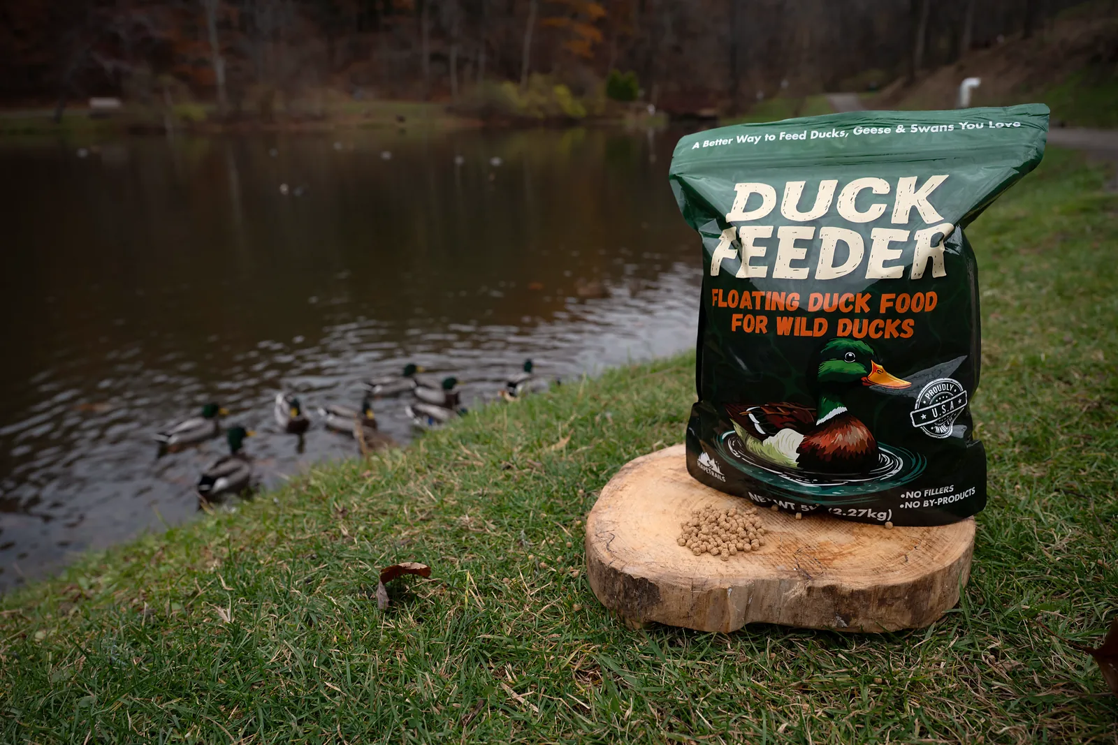 A bag of Duck Feeder standing on a wood slice by a pond with ducks on the water
